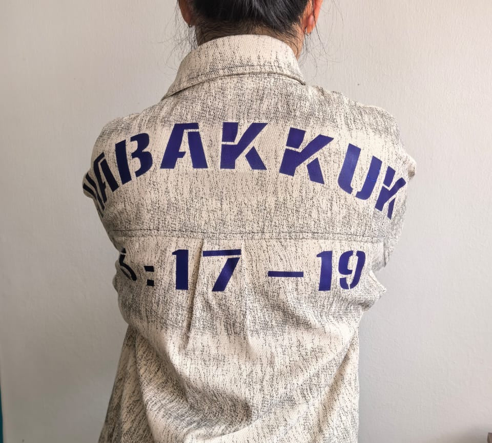 Person wearing a jacket with 'HABAKUK' printed on the back against a plain background